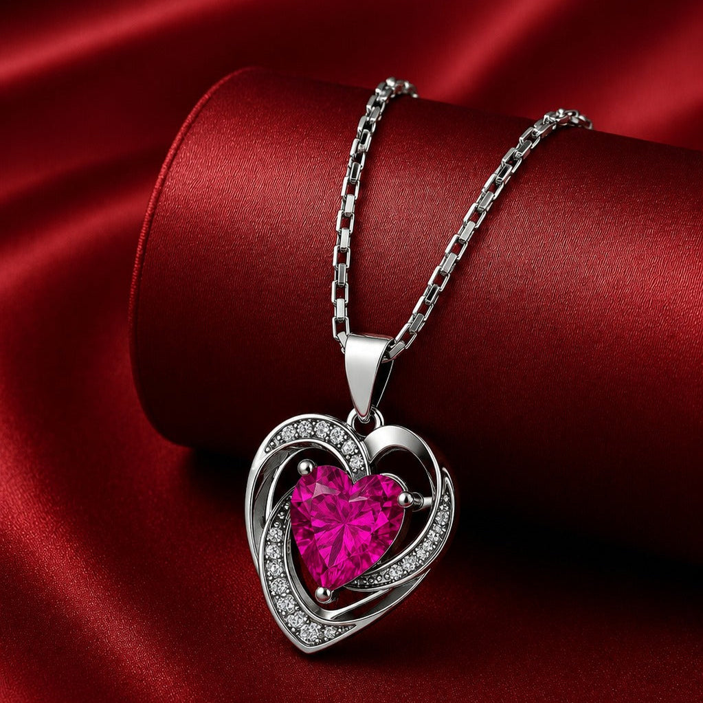Heart-shaped pendant with a pink gemstone on a red satin background